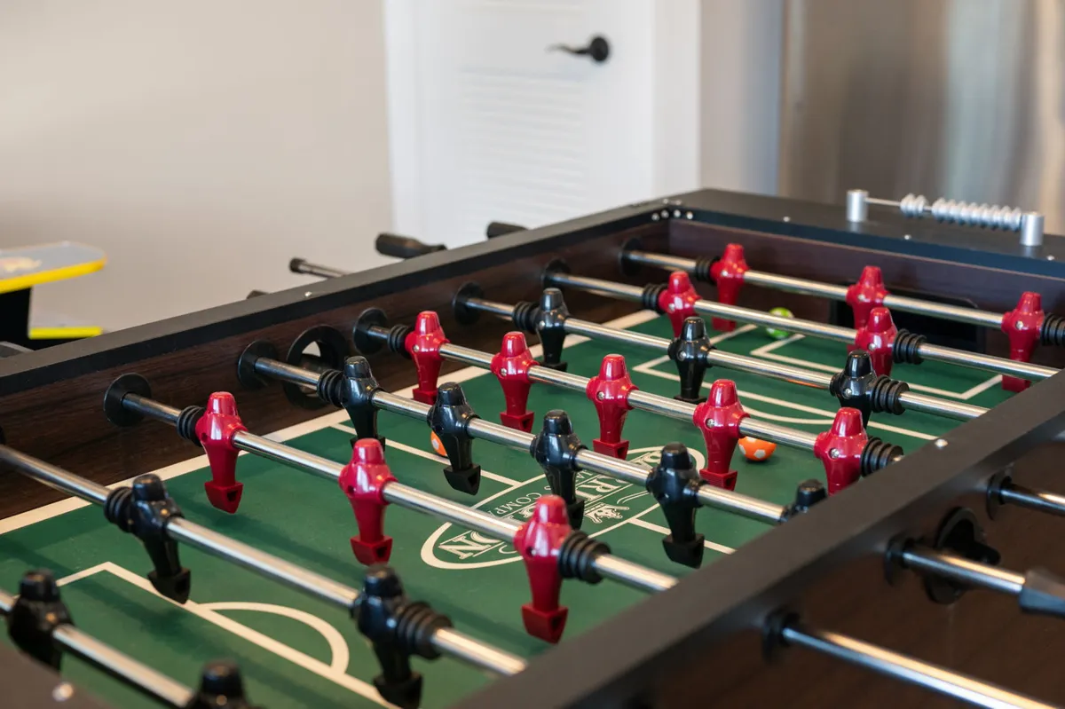 A lively foosball table sits ready for play, its colorful player figures contrasting with the green surface. The setup exudes a playful atmosphere, hinting at moments of fun and connection indoors after daylight adventures.