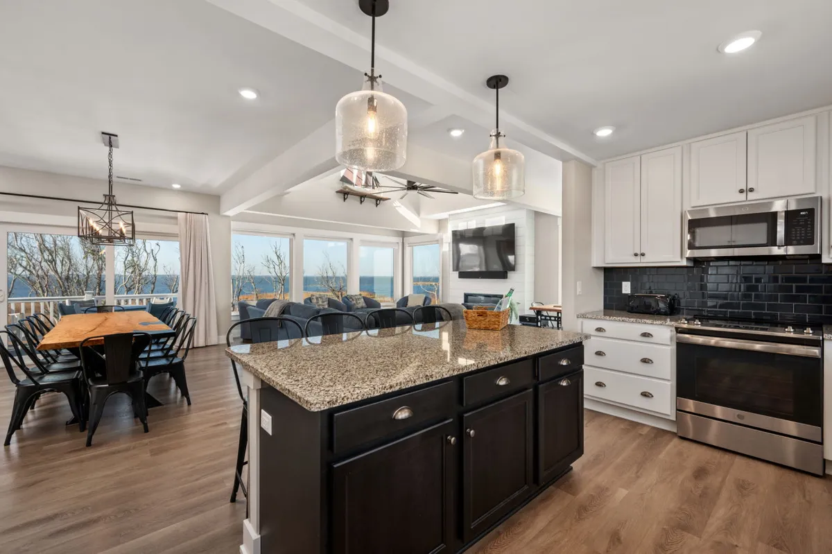 A welcoming kitchen and dining area paired with a granite kitchen island, comfortable dining set, and expansive windows offering scenic views. The space is bright, inviting, and seamlessly connected to the living spaces, ideal for festive meals and casual brunches.