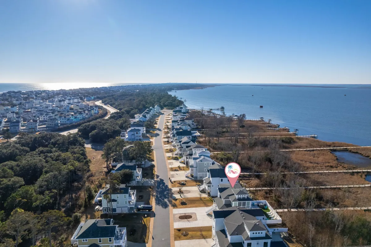 A tranquil exterior scene showing coastal homes, a waterfront view, and a road leading towards the coast. The atmosphere is peaceful, evoking a sense of seaside community and exploration. The open sky and water suggest opportunities for walking, community gatherings, and enjoying local attractions nearby.