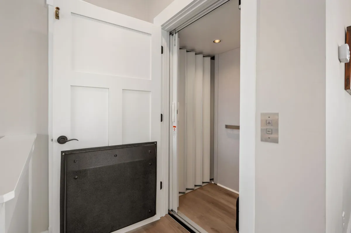A sleek, contemporary elevator entrance with modern door design and clean lines, set within a bright interior. The elevator signals accessibility from the garage up to main and upper floors, underscoring inclusivity and thoughtful amenities.